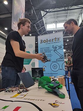 Zwei Männer stehen sich gegenüber und sprechen über Robotik-Bauteile